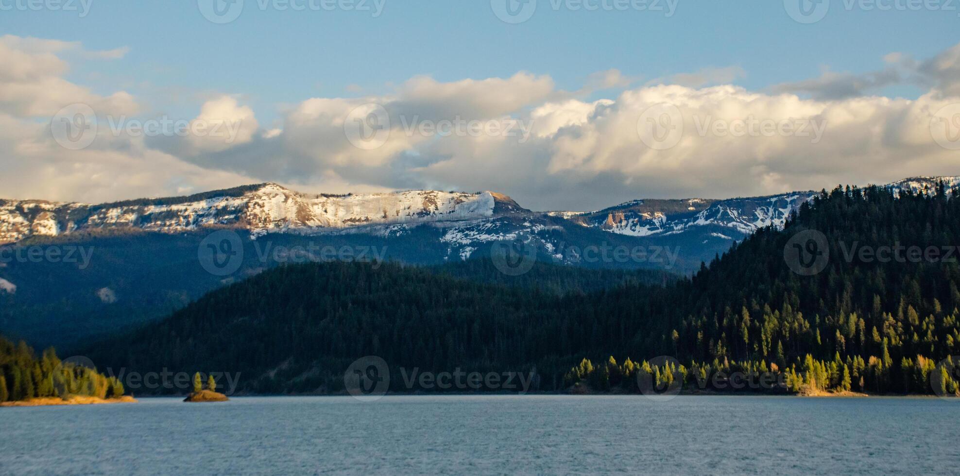 Mountains in the snow, overgrown with wood. Thick clouds over the mountains. photo