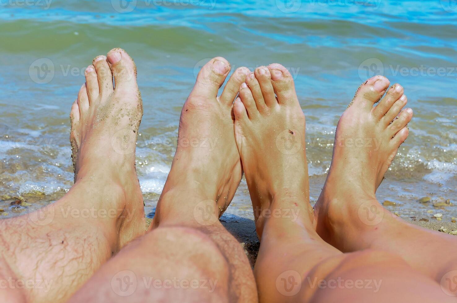 Female and male legs of people sunbathing near water photo