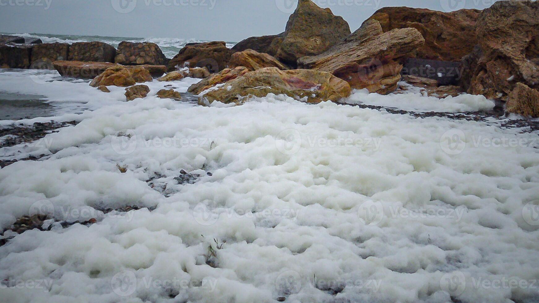 Eutrophication and pollution of the sea, waves with dirty foam roll ashore during a storm, Black Sea photo