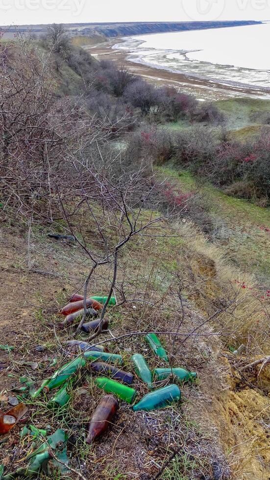 Nature pollution, garbage and empty bottles on the shore of the Tiligul estuary photo