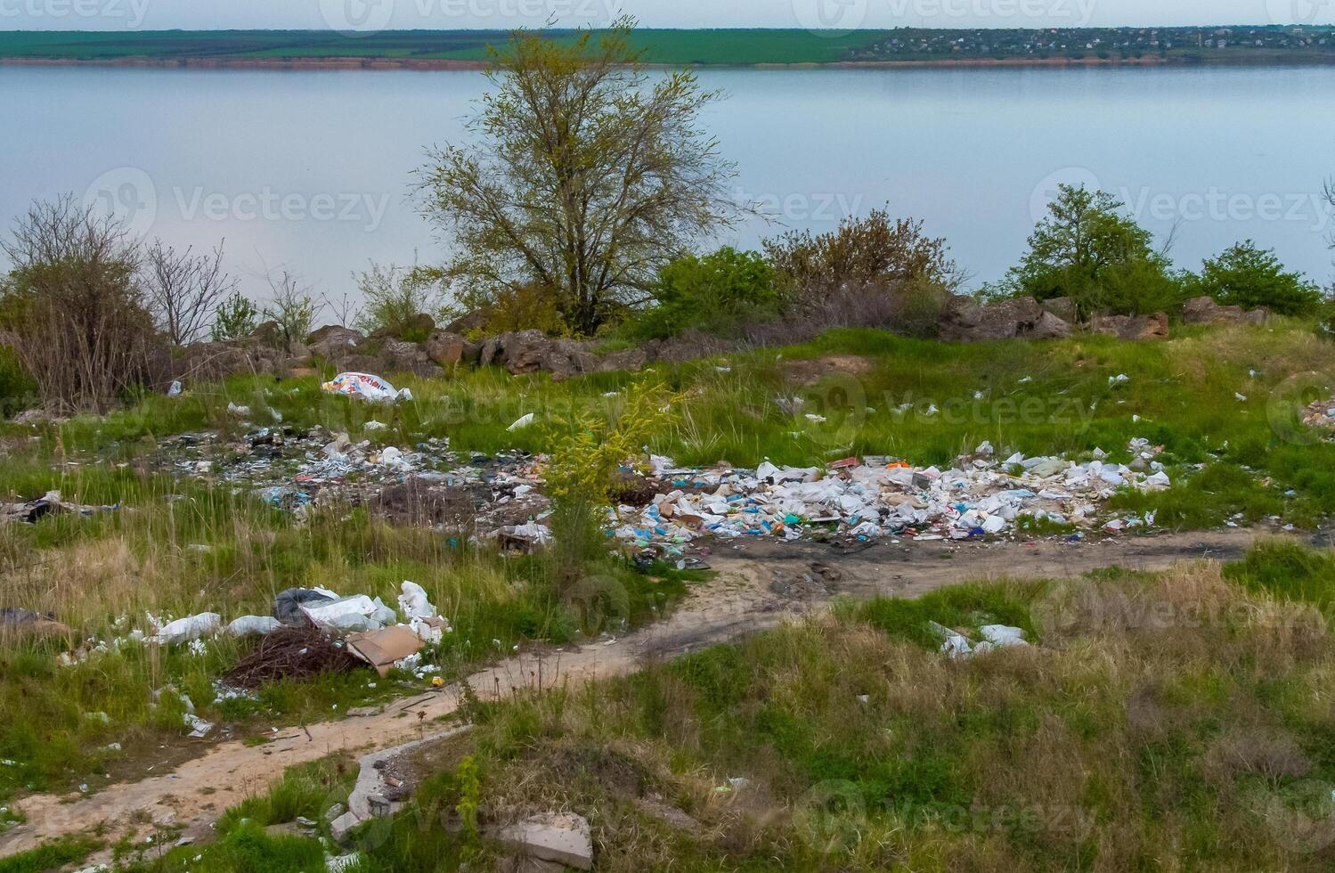 Heaps of plastic trash on the shore of the reservoir. Ecology of nature photo