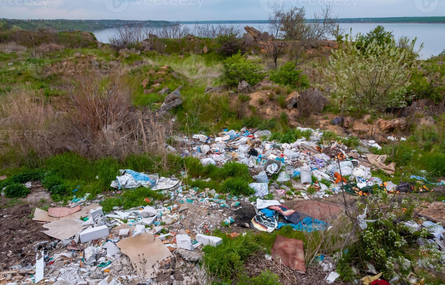 Heaps of plastic trash on the shore of the reservoir. Ecology of nature photo