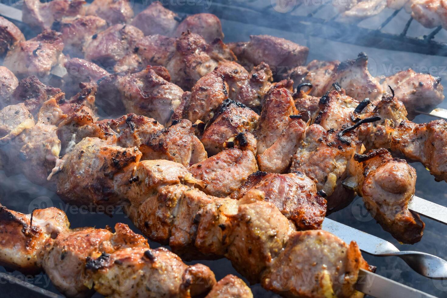 Pork meat is fried on smoking coals in the grill photo