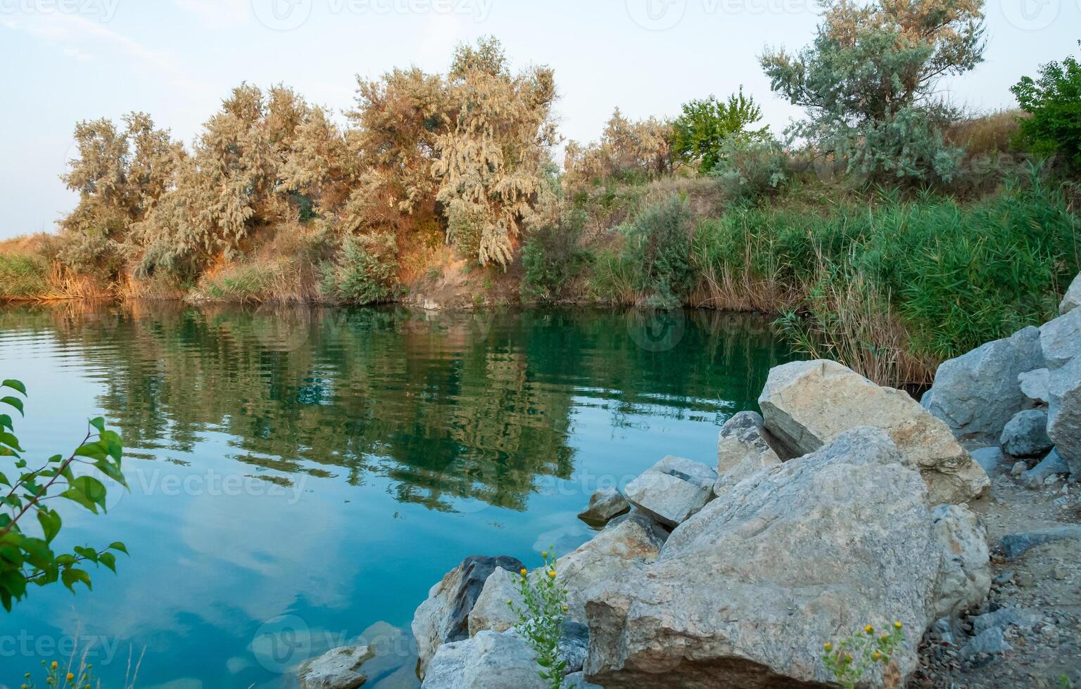 Reflection of trees in the clear water of a flooded granite quarry, Ukraine photo
