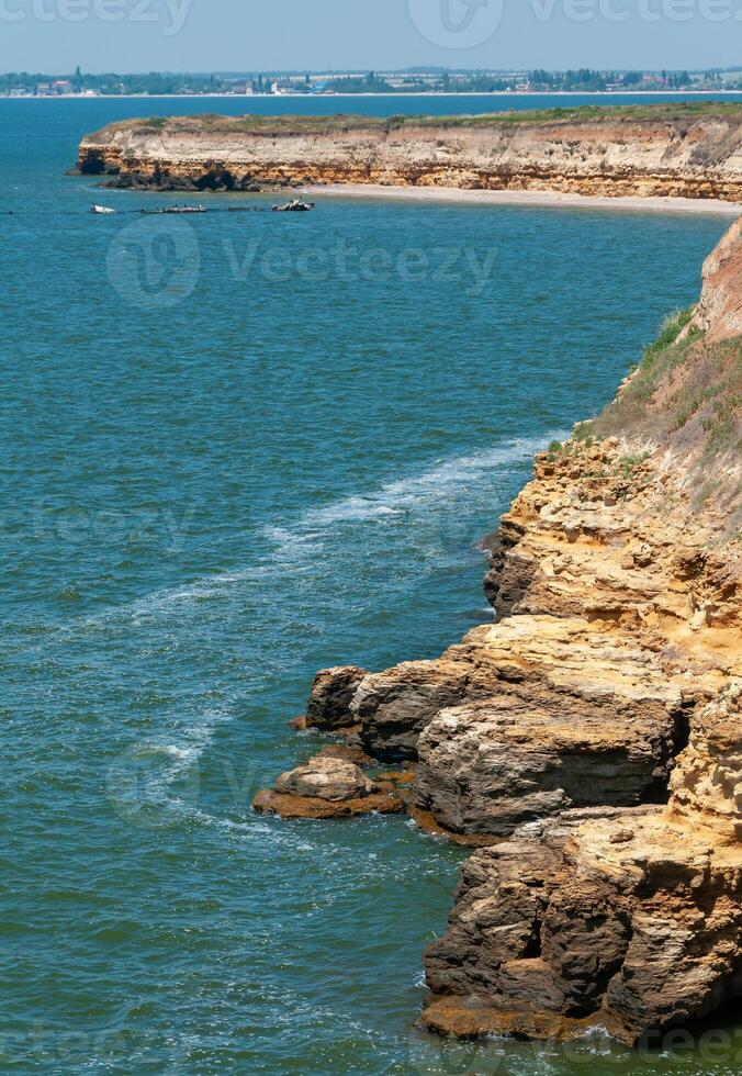 Steep clayey and shell rock shore overgrown with wild steppe vegetation on the island of Berezan, Ukraine photo
