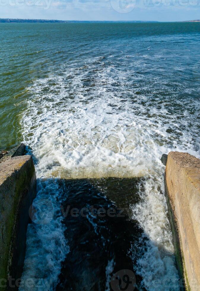 Waste water is poured into the estuary, dirty foam. Ecological problems of the reservoir. Hadzhibey estuary, Ukraine photo