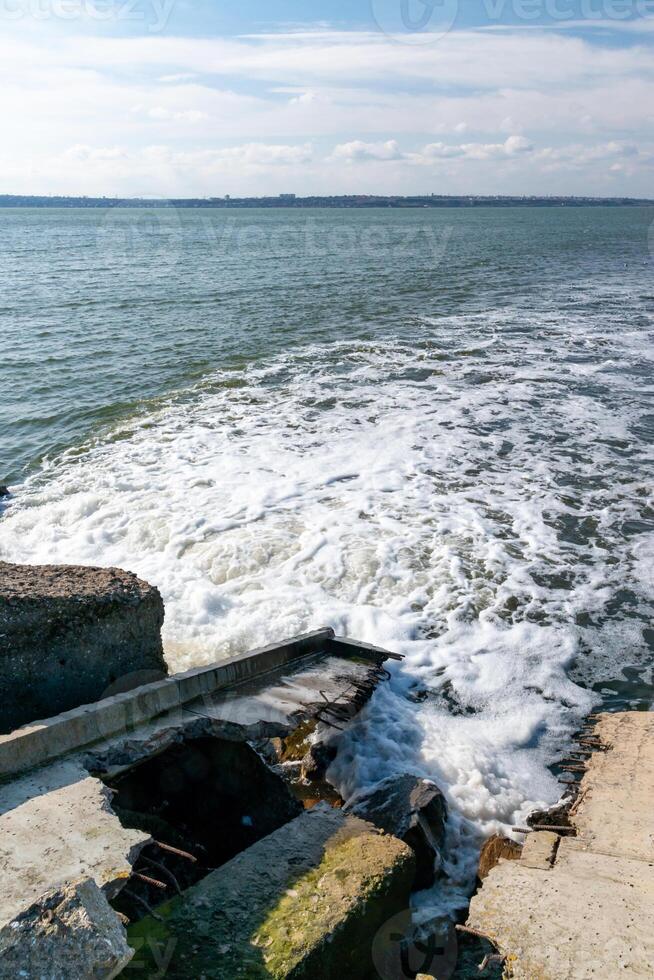 Waste water is poured into the estuary, dirty foam. Ecological problems of the reservoir. Hadzhibey estuary, Ukraine photo