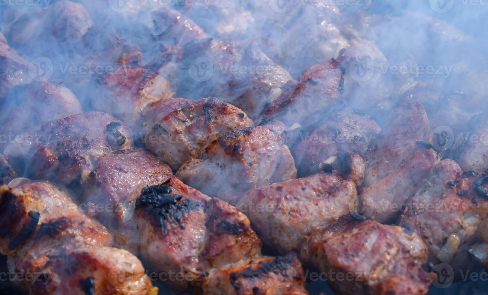 Pork meat is fried on smoking coals in the grill photo