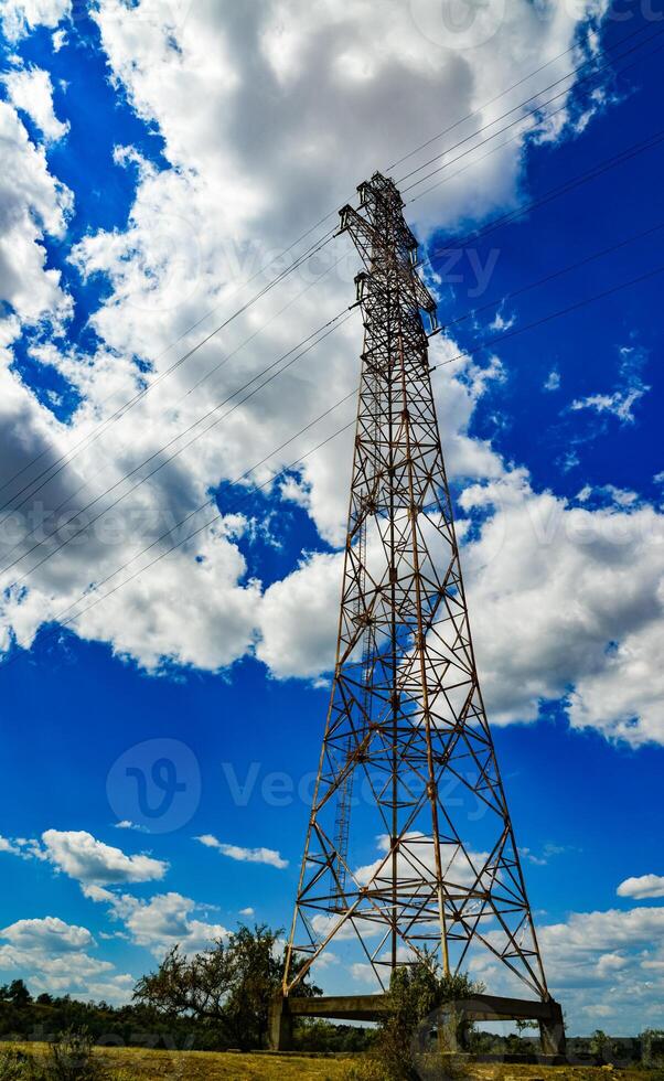 Iron structures of a high-voltage power line against a blue sky with clouds photo