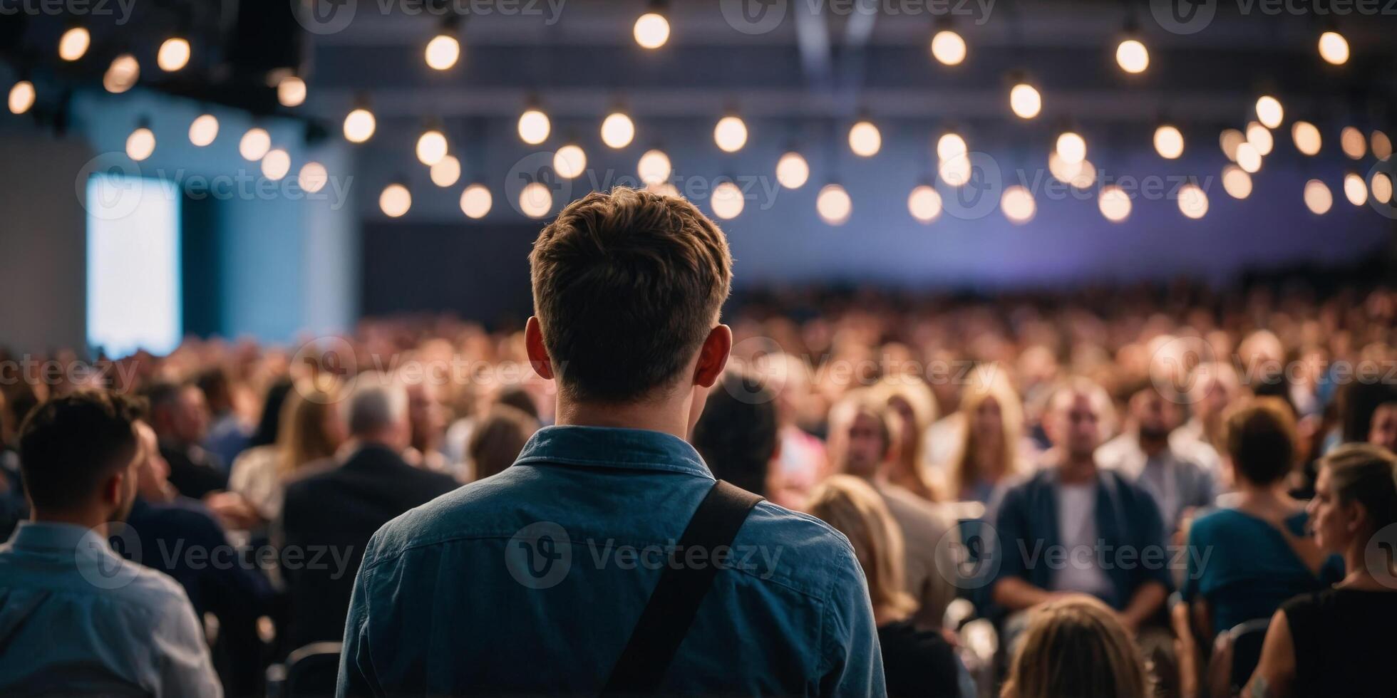 Audience perspective of a live event with focus on one attendee looking towards the stage. photo