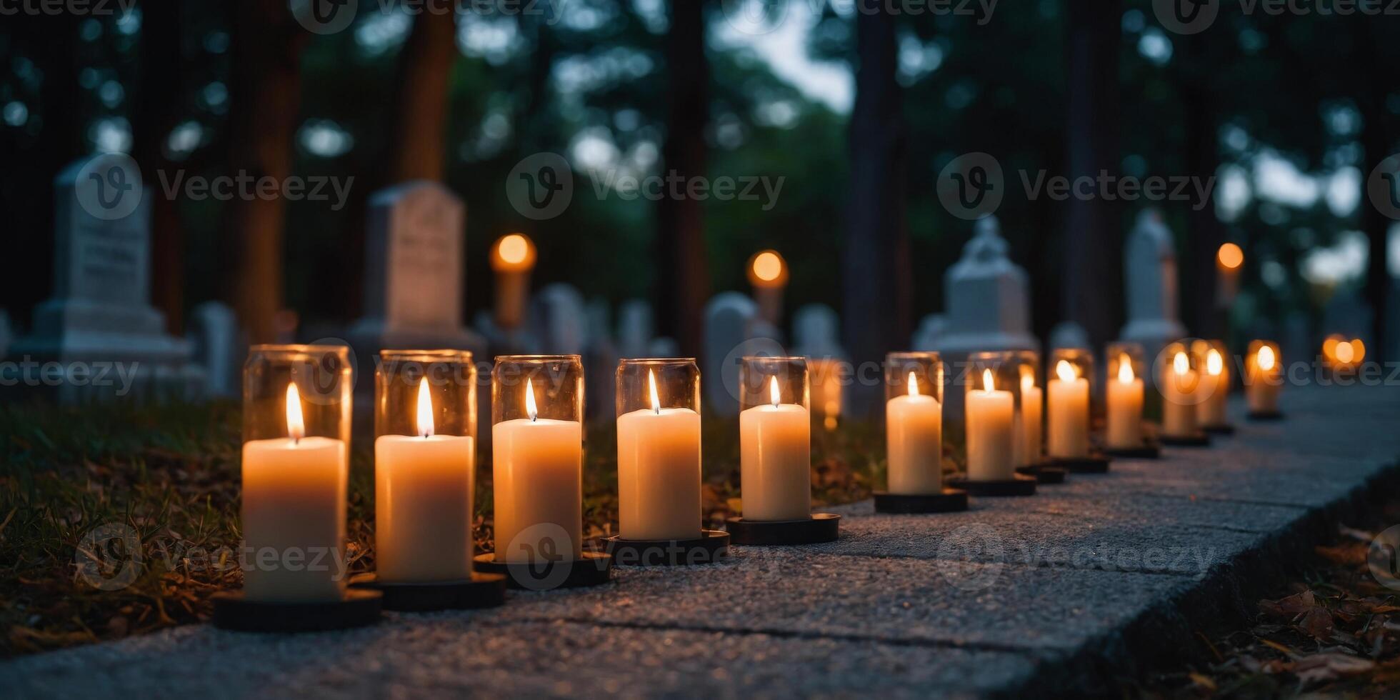 A row of candles are lit on a path in front of a cemetery. photo