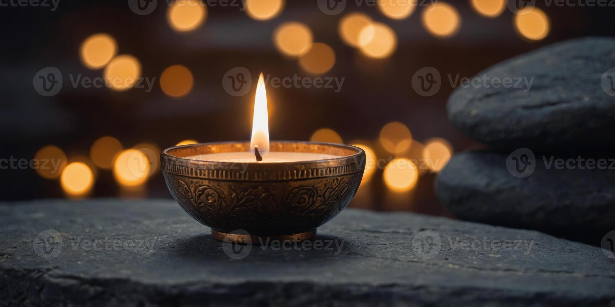 A candle is lit in a small bowl on a stone ledge. photo