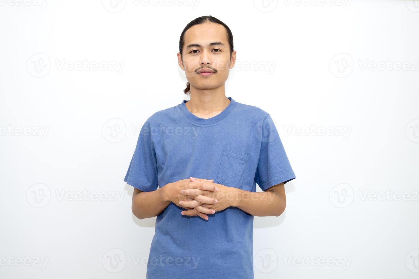 Smiling Asian man wearing dark blue t-shirt standing with crossed fingers and facing forward. isolated in white background photo