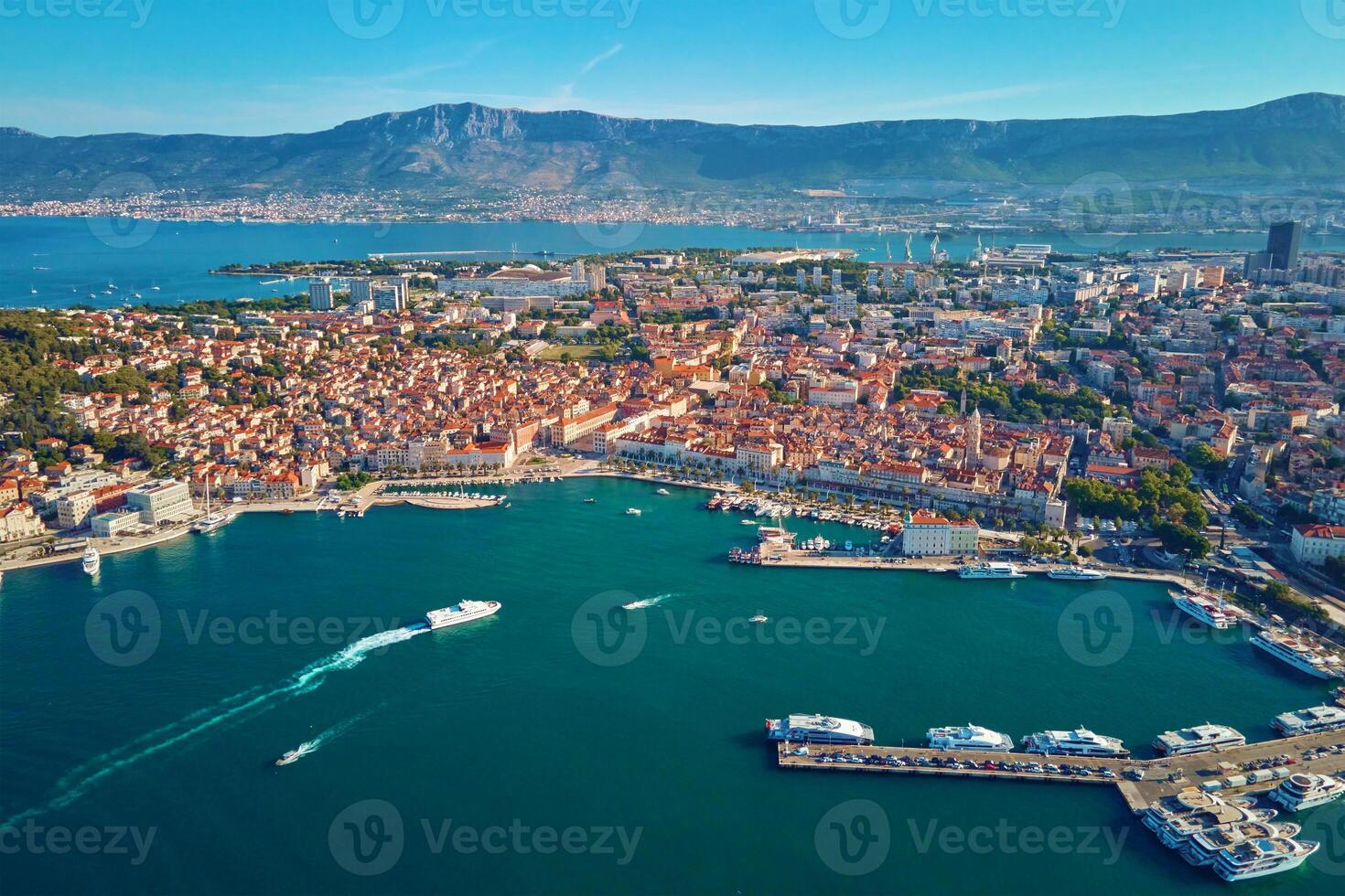 Aerial view of Split, Croatia. Cityscape of coastal touristic city with harbor with mountains in background. Old town with historical red roof tiled buildings near Adriatic Sea photo