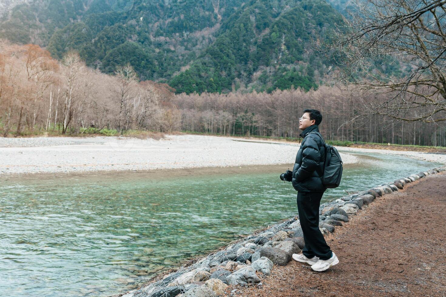 man tourist travel Kamikochi National Park, happy Traveler sightseeing Azusa river with mountain, Nagano Prefecture, Japan. Landmark for tourists attraction. Japan Travel, Destination and Vacation photo