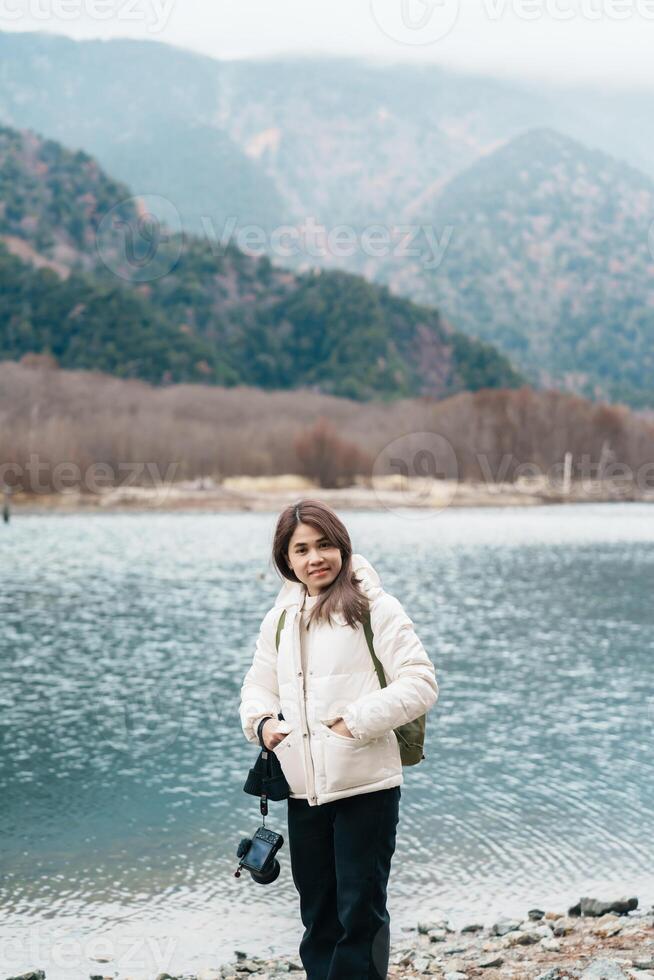 Woman tourist travel Kamikochi National Park, happy Traveler sightseeing Taisho pond with mountain, Nagano Prefecture, Japan. Landmark for tourists attraction. Japan Travel, Destination and Vacation photo