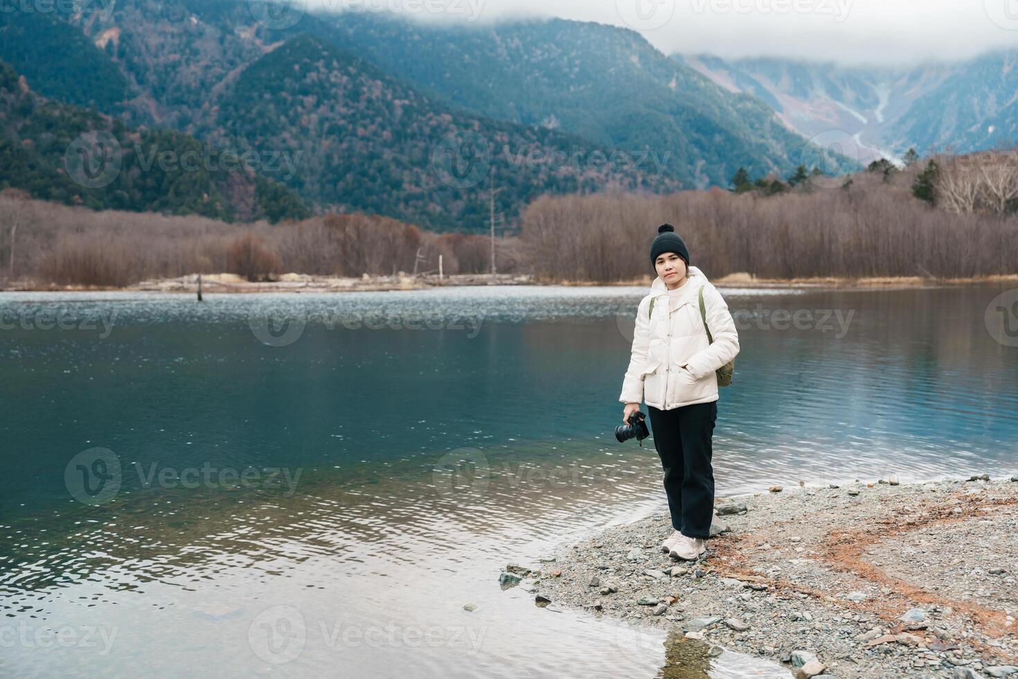 Woman tourist travel Kamikochi National Park, happy Traveler sightseeing Taisho pond with mountain, Nagano Prefecture, Japan. Landmark for tourists attraction. Japan Travel, Destination and Vacation photo