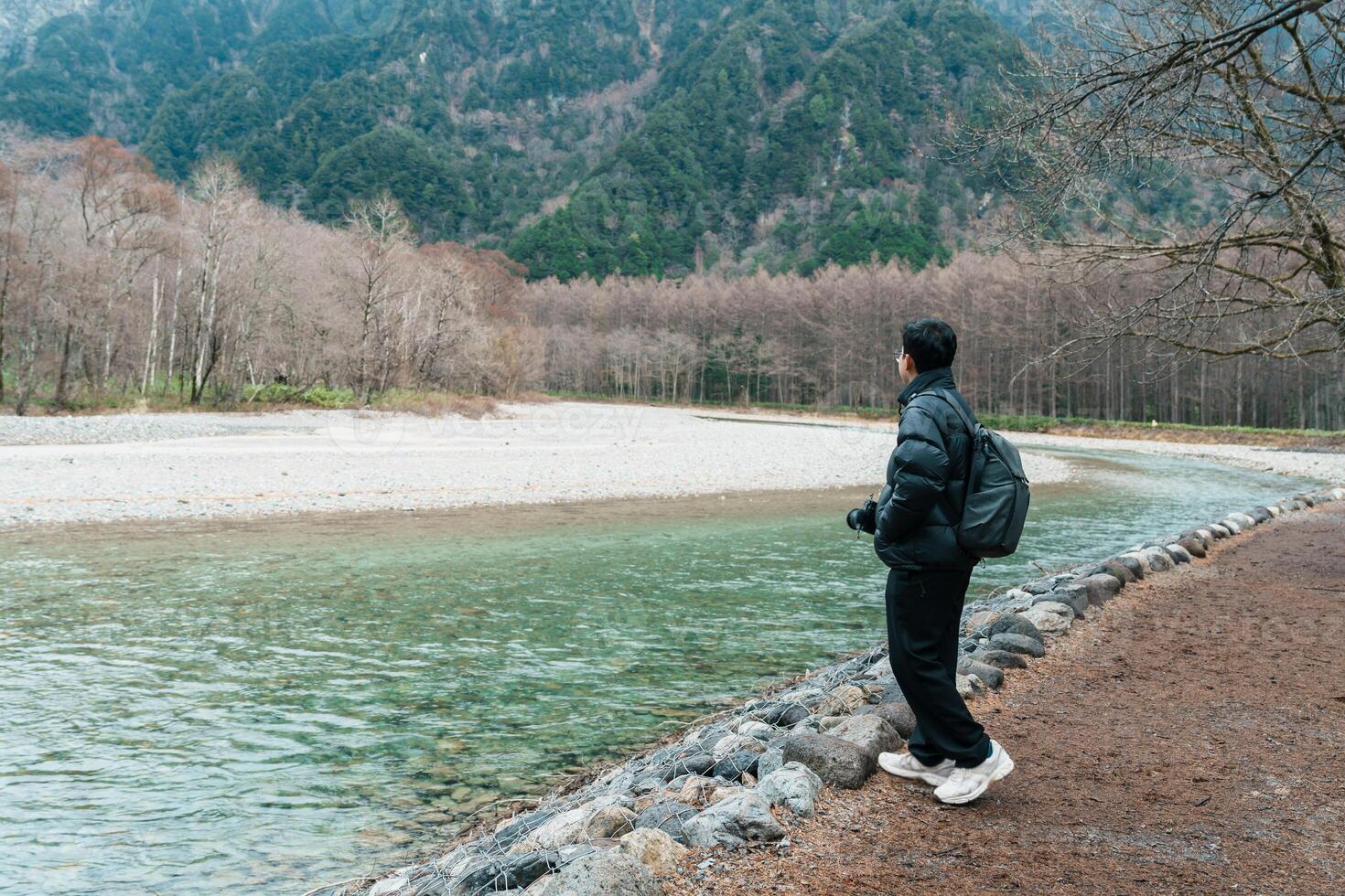 man tourist travel Kamikochi National Park, happy Traveler sightseeing Azusa river with mountain, Nagano Prefecture, Japan. Landmark for tourists attraction. Japan Travel, Destination and Vacation photo