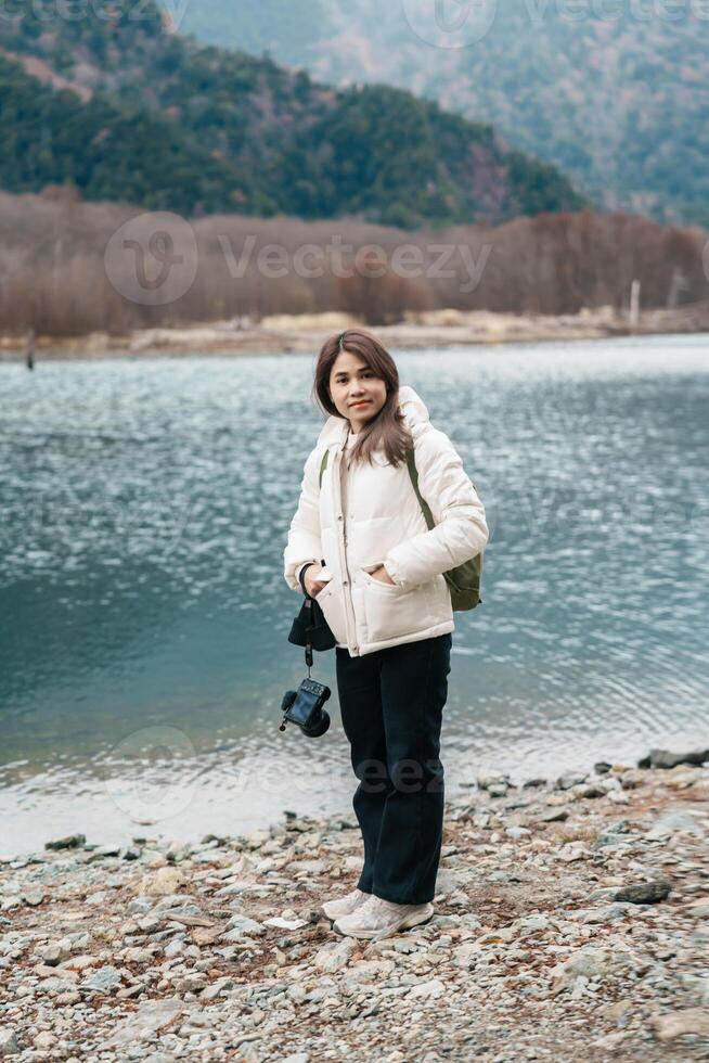 Woman tourist travel Kamikochi National Park, happy Traveler sightseeing Taisho pond with mountain, Nagano Prefecture, Japan. Landmark for tourists attraction. Japan Travel, Destination and Vacation photo
