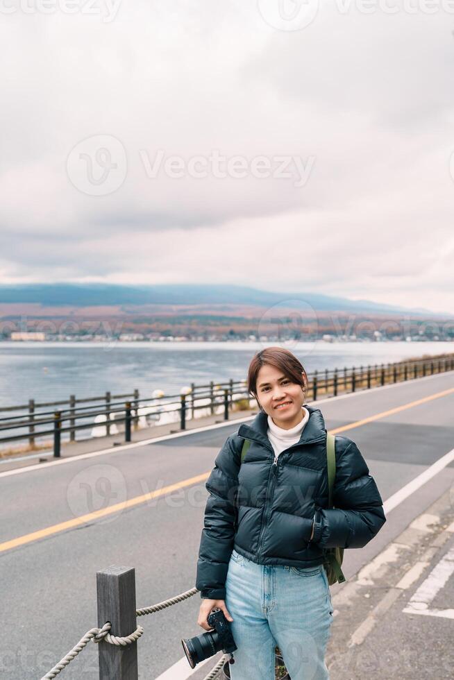 Woman tourist with Mt Fuji at Lake Yamanaka, happy Traveler sightseeing Mount Fuji in Yamanakako village, Yamanashi, Japan. Landmark for tourists attraction. Japan Travel, Destination and Vacation photo