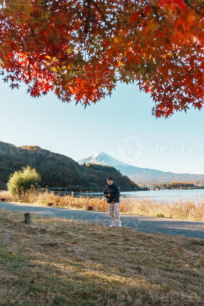 man tourist with Fuji Mountain at Lake Kawaguchi in Autumn season, happy Traveler travel Mount Fuji, Yamanashi, Japan. Landmark for tourists attraction. Japan Travel, Destination and Vacation photo