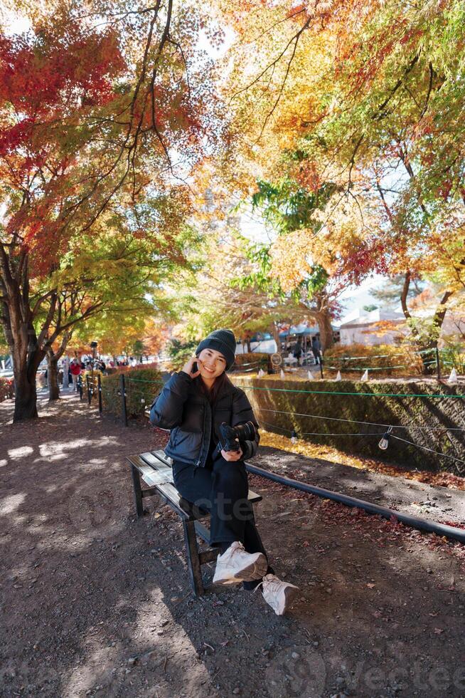 Woman tourist at Momiji Kairo in Autumn season, happy Traveler travel Maple Corridor at lake Kawaguchi, Yamanashi, Japan. Landmark for tourists attraction. Japan Travel, Destination and Vacation photo