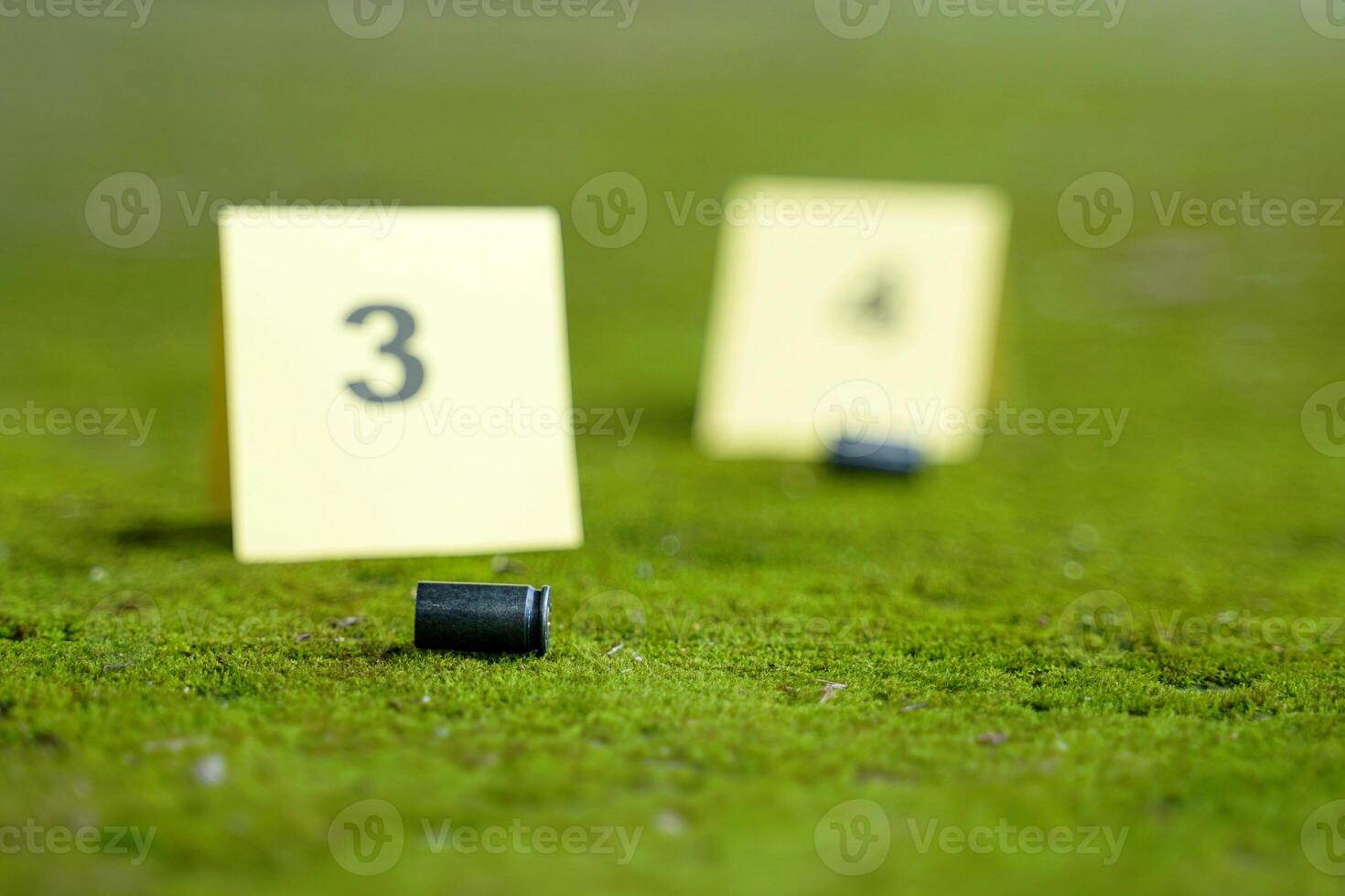 Bullet casings fell on the moss growing on the cement floor and blurry background of the evidence number plate at the scene. Concept of investigation, forensic science. photo