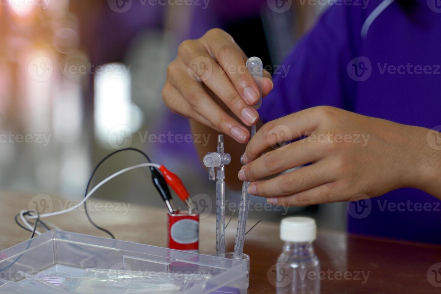 Asian school children conduct science experiments with kits Electrolysis, which is a method of electrically separating solutions to separate hydrogen and oxygen gases from water. photo