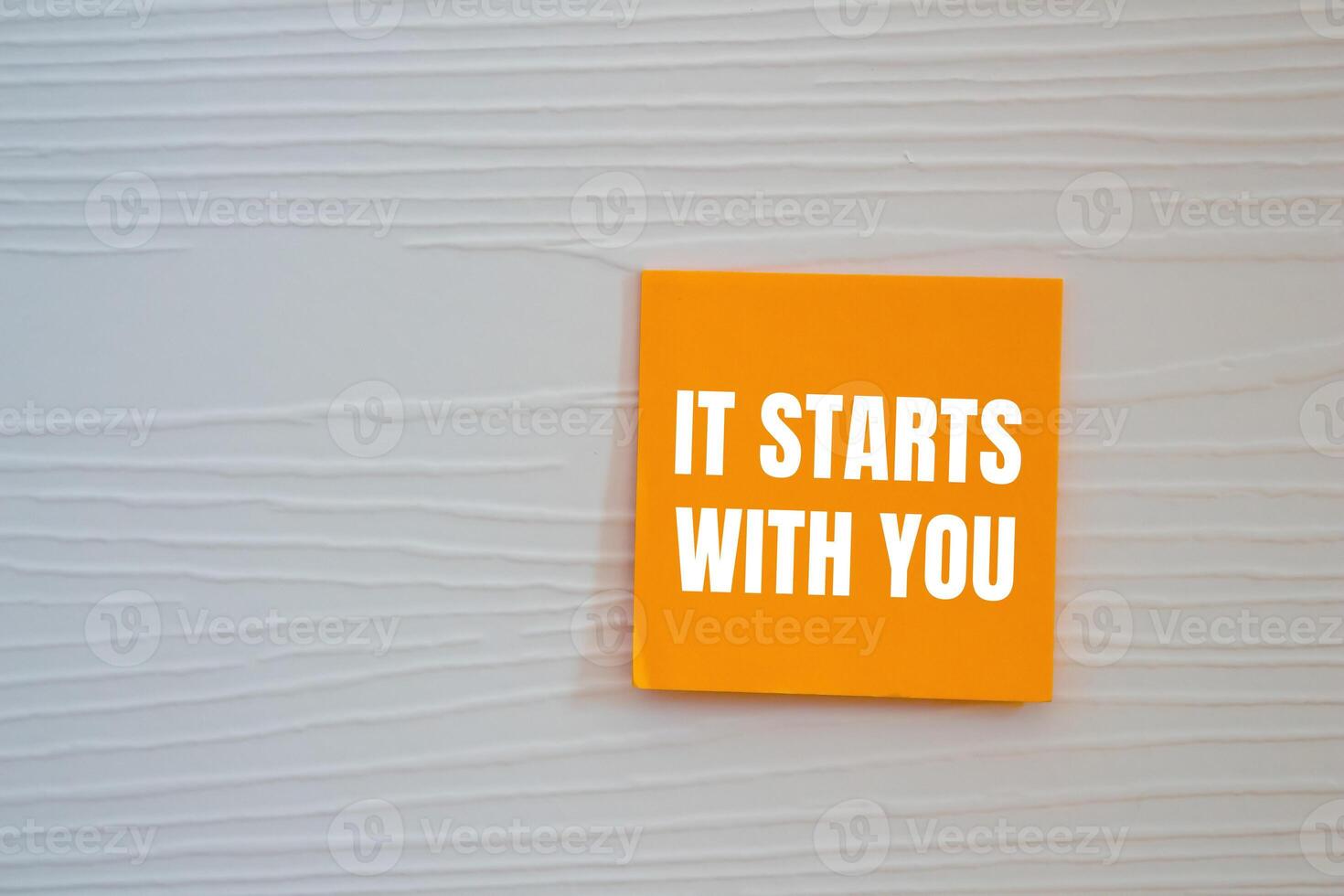 It starts with you message written on orange paper on white wooden background. Conceptual it starts with you symbol. photo