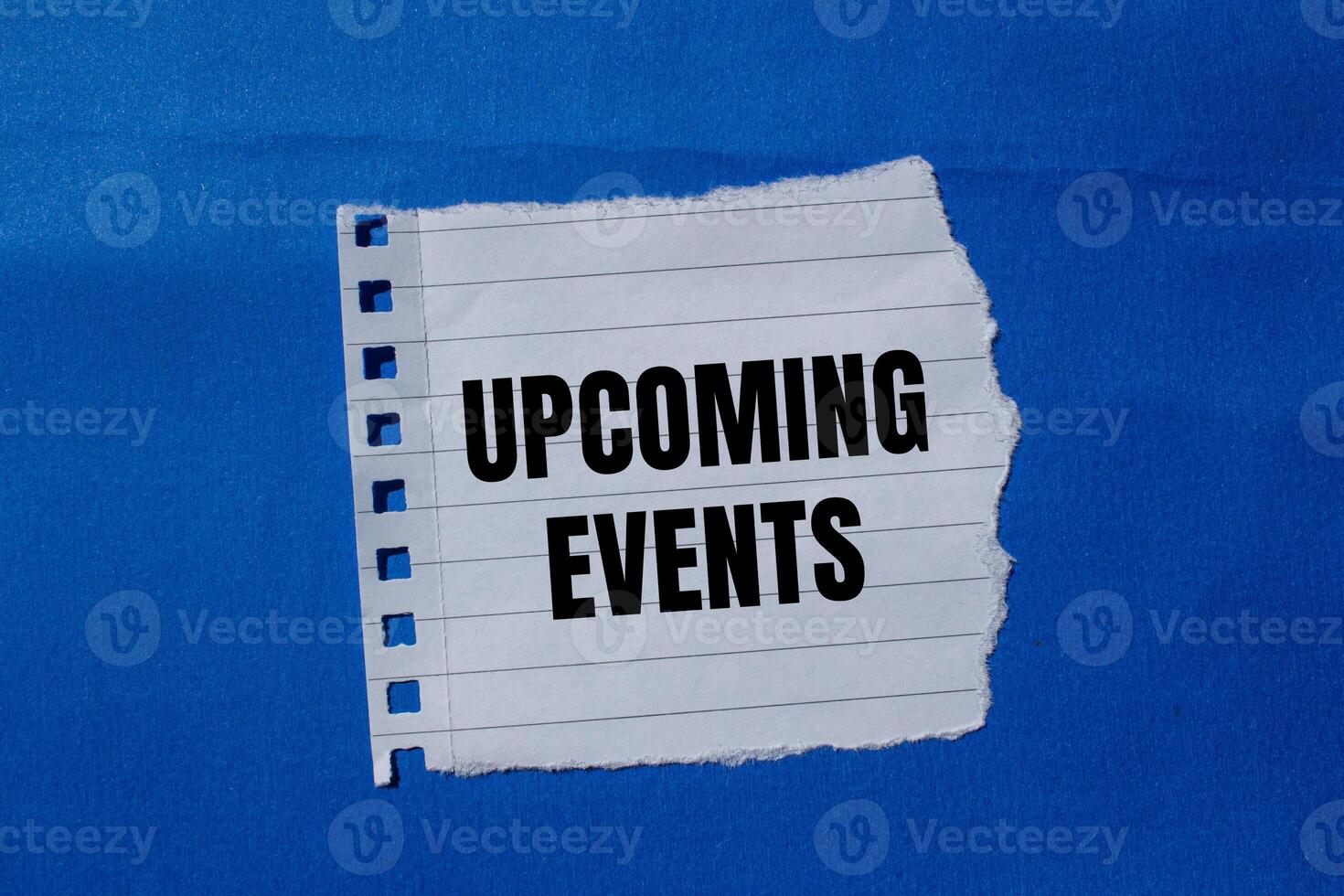 Upcoming events message written on ripped torn paper piece with blue background. Conceptual upcoming events symbol. Copy space. photo