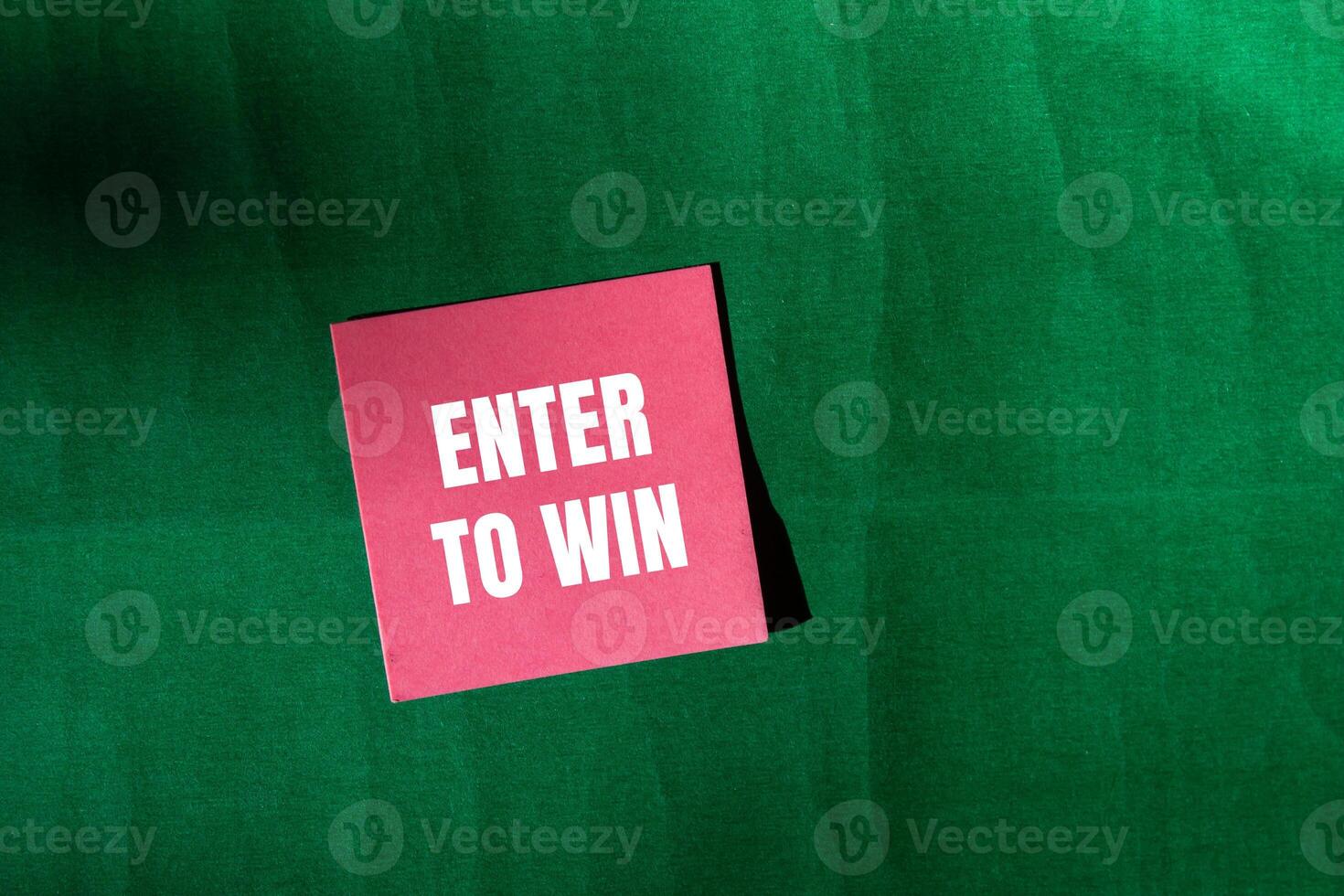 Enter to win message written on pink paper with green background. Conceptual enter to win symbol. Copy space. photo