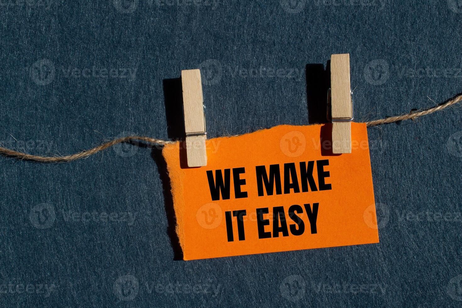 We make it easy message written on ripped torn orange paper piece with gray background. Conceptual we make it easy symbol. Copy space. photo