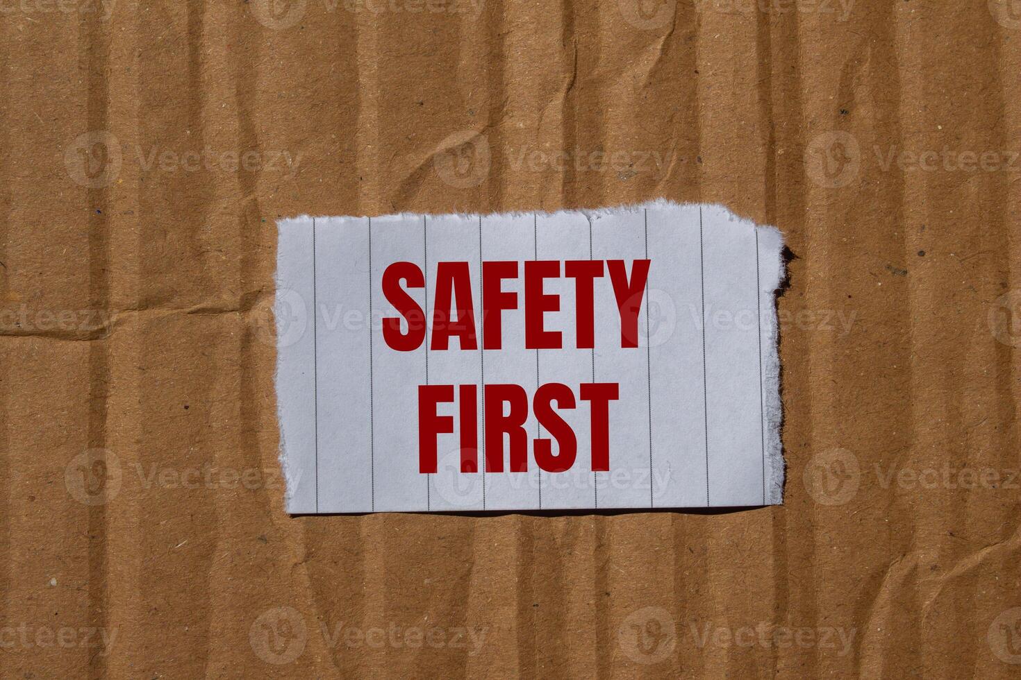 Safety first message written on ripped torn paper with cardboard background. Conceptual safety first symbol. Copy space. photo