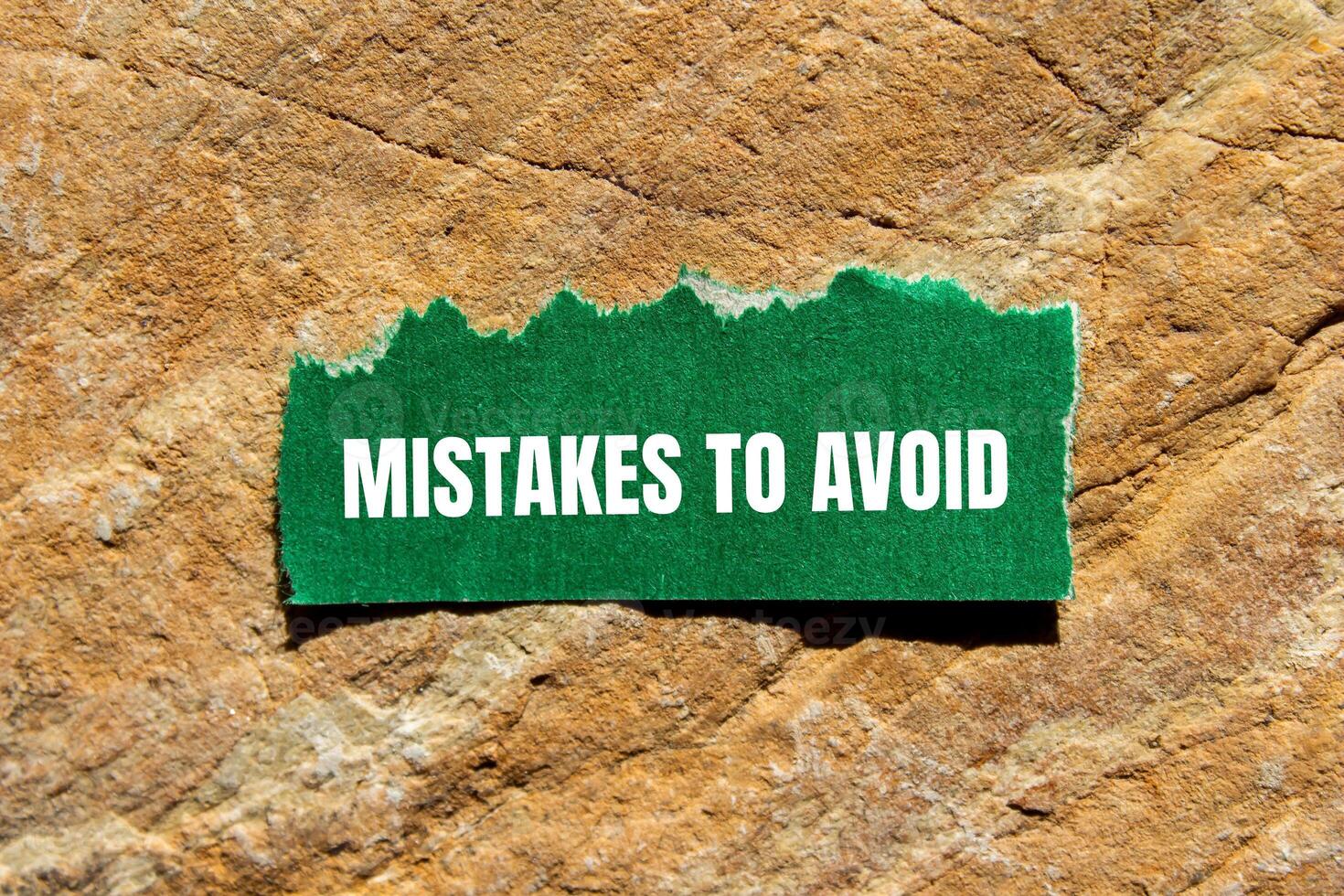 Mistakes to avoid message written on ripped torn green paper piece on stone background. Conceptual mistakes to avoid symbol. Copy space. photo