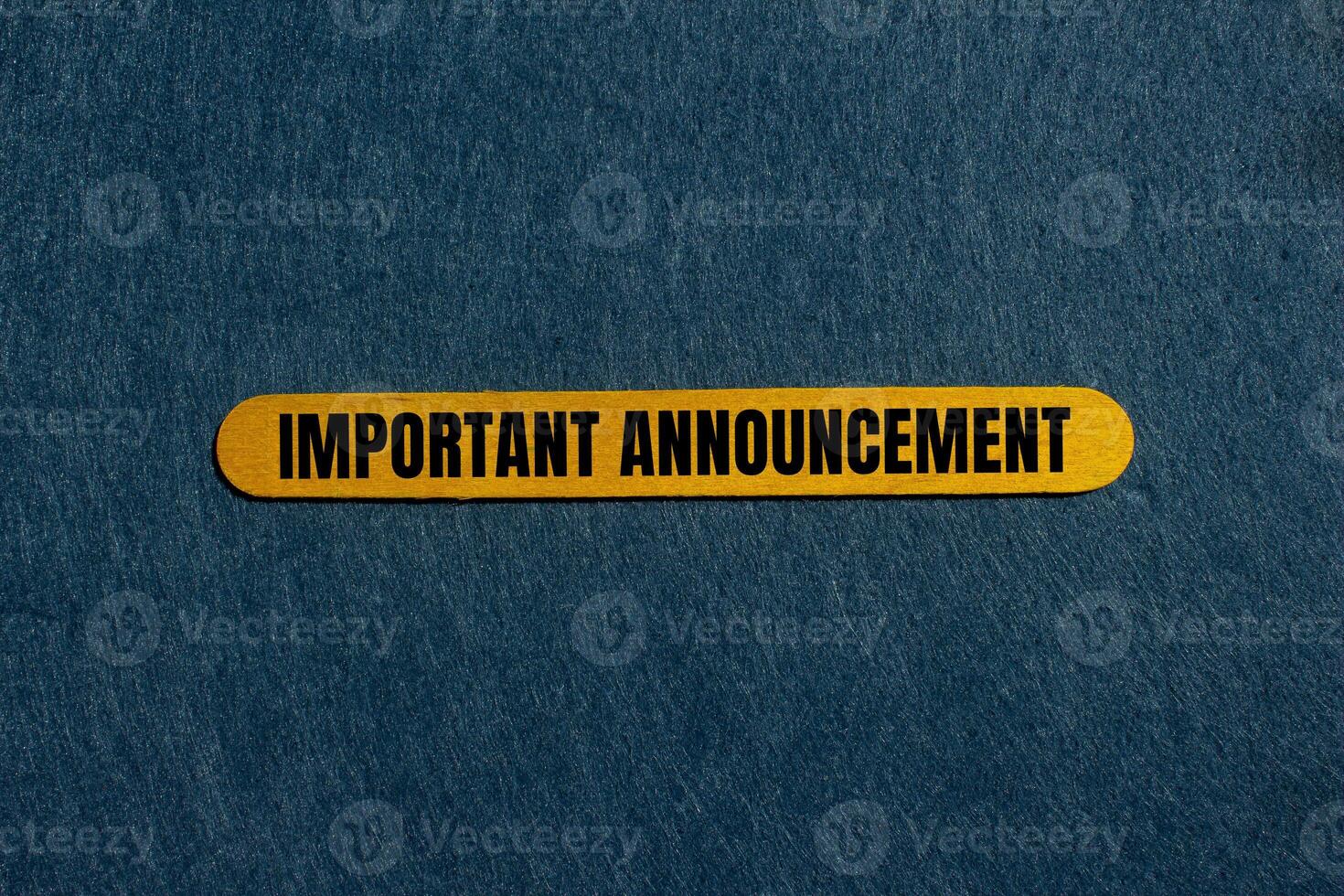 Important announcement message written on yellow wooden stick with gray background. Conceptual important announcement symbol. Copy space. photo