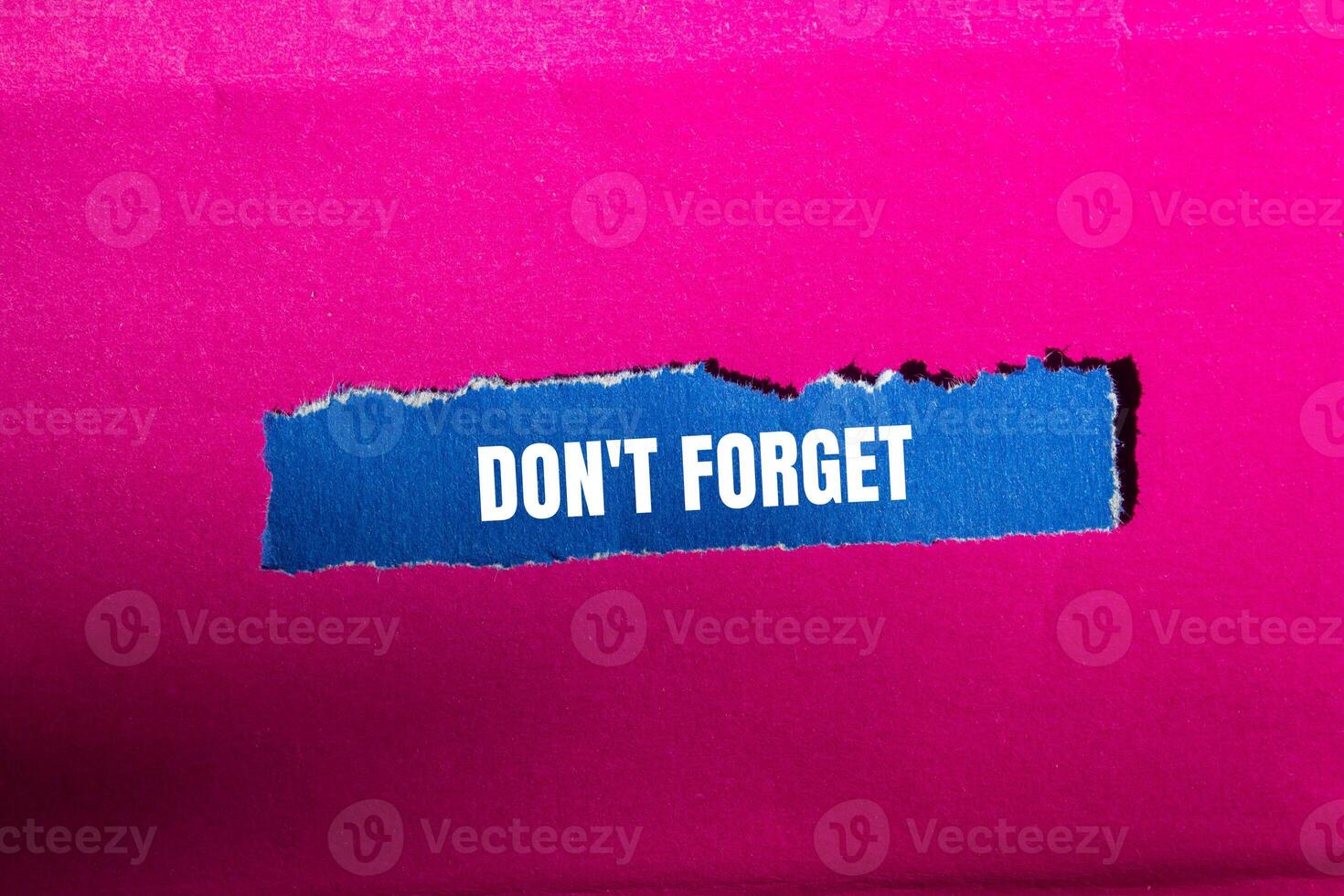 Don't forget message written on ripped torn blue paper piece with pink background. Conceptual don't forget symbol. Copy space. photo