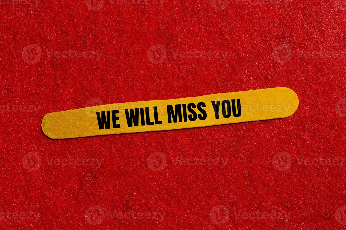 We will miss you message written on yellow wooden stick with red background. Conceptual we will miss you symbol. Copy space. photo