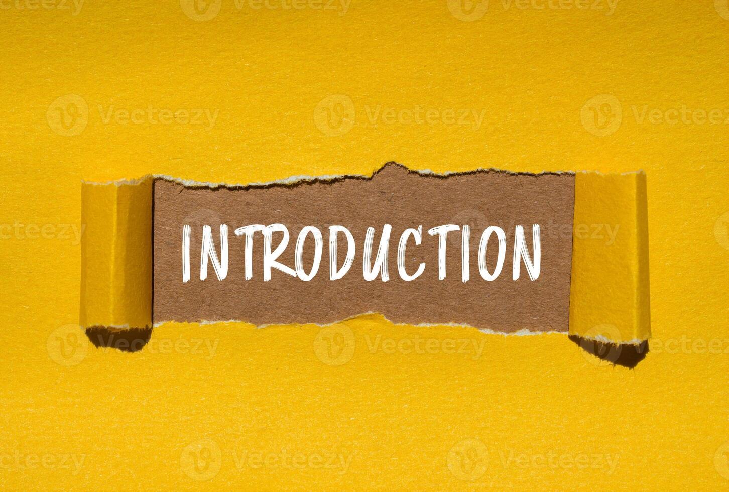 Introduction message written on ripped torn yellow paper with brown background. Conceptual introduction symbol. Copy space. photo