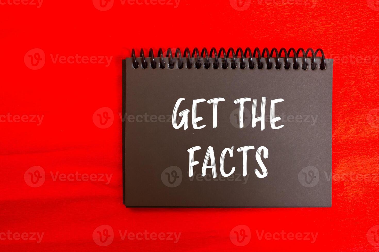 Get the facts message written on black notebook page with red background. Conceptual get the facts symbol. Copy space. photo
