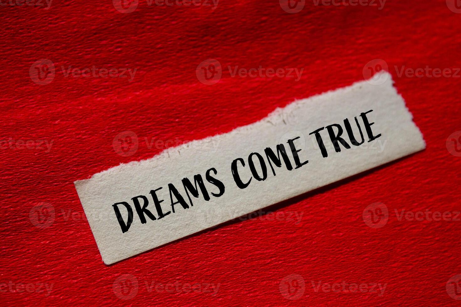 Dreams come true message written on torn paper with red background. Conceptual dreams come true symbol. Copy space. photo