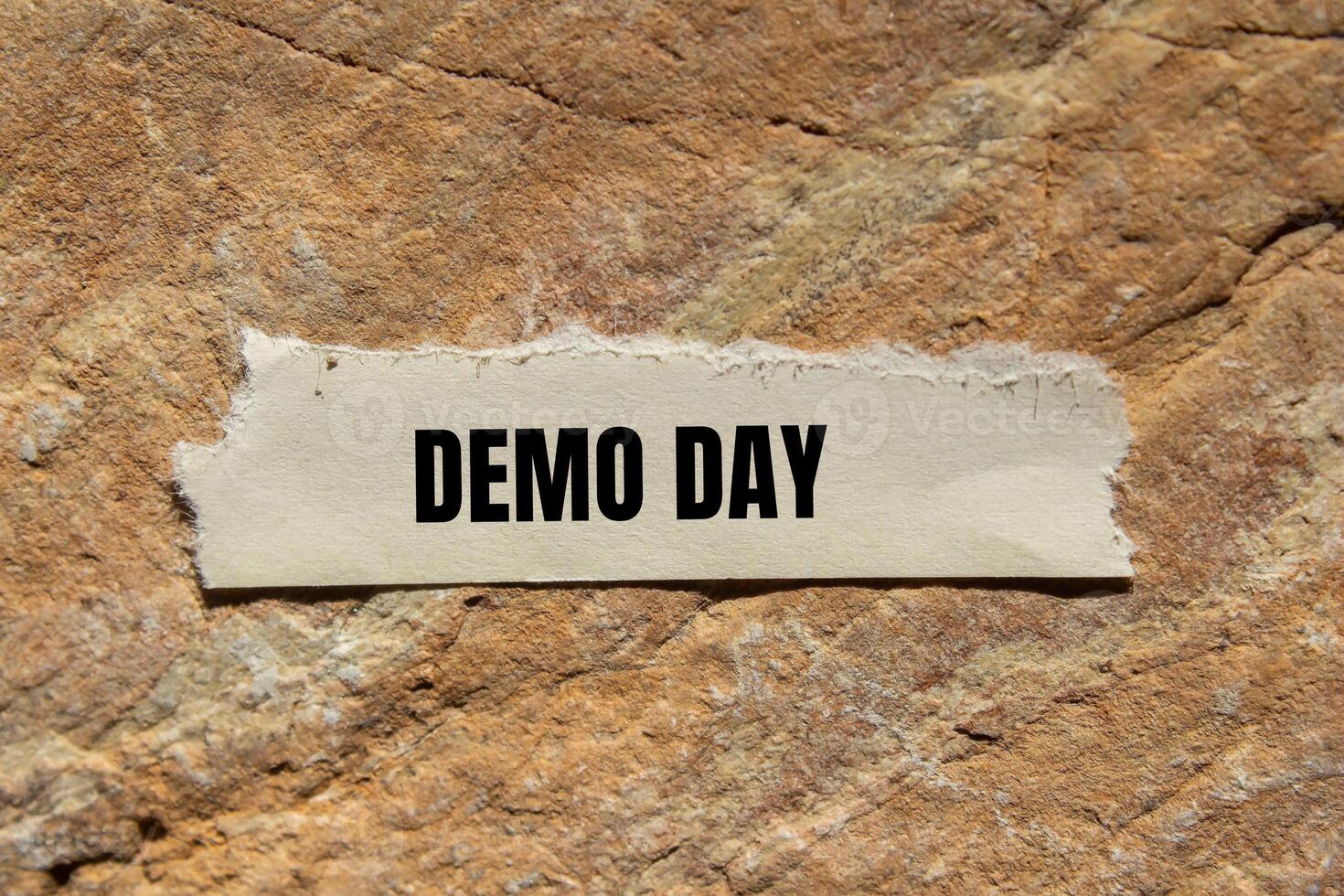 Demo day message written on ripped torn paper piece on stone background. Conceptual demo day symbol. Copy space. photo