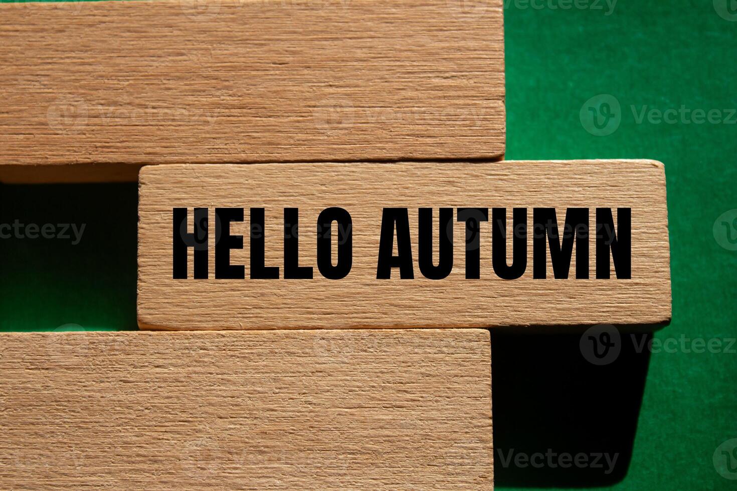 Hello autumn message written on wooden blocks with green background. Conceptual hello autumn symbol. Copy space. photo