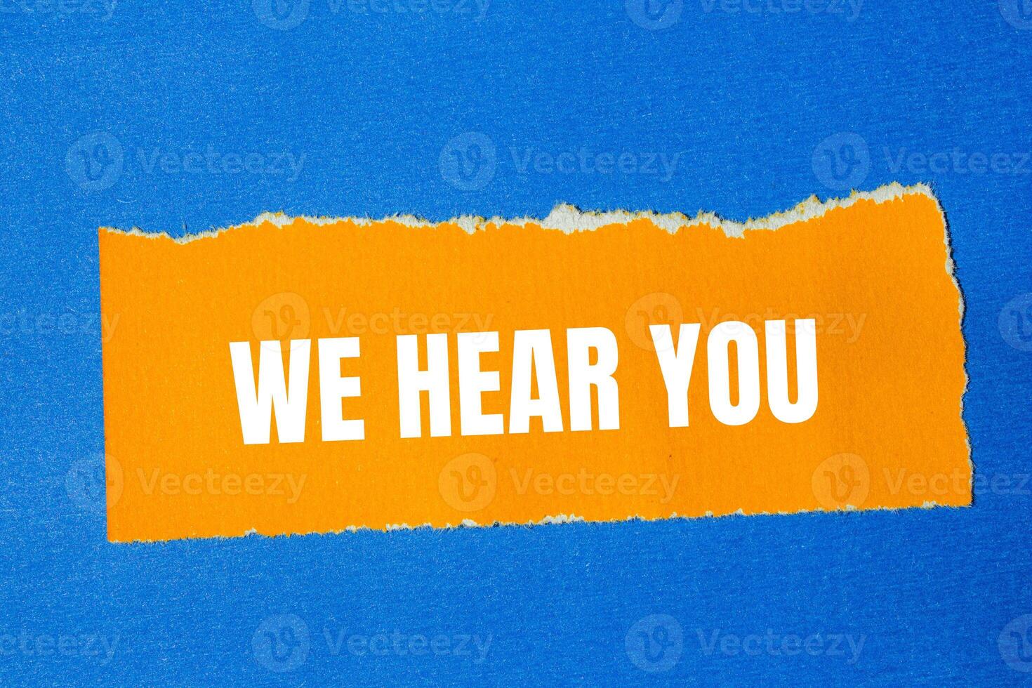We hear you message written on ripped torn orange paper with blue background. Conceptual we hear you symbol. Copy space. photo