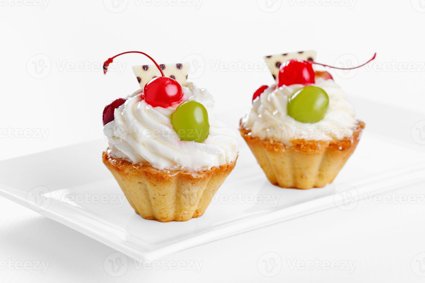 Beautiful cream cakes with cherries and grapes on a plate on a white background photo