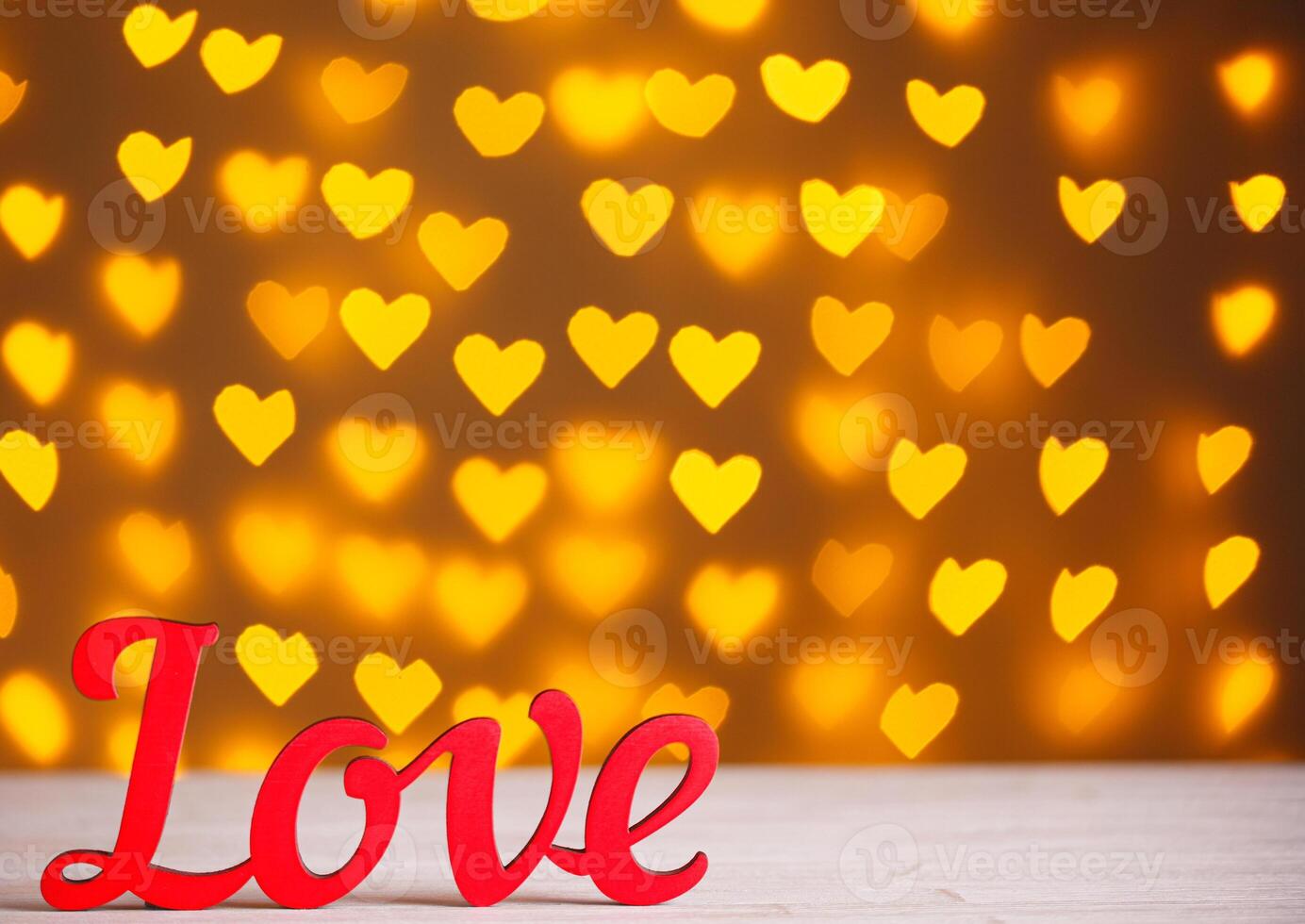 the inscription Love on a wooden background with beautiful hearts made of lights on a blurred background photo