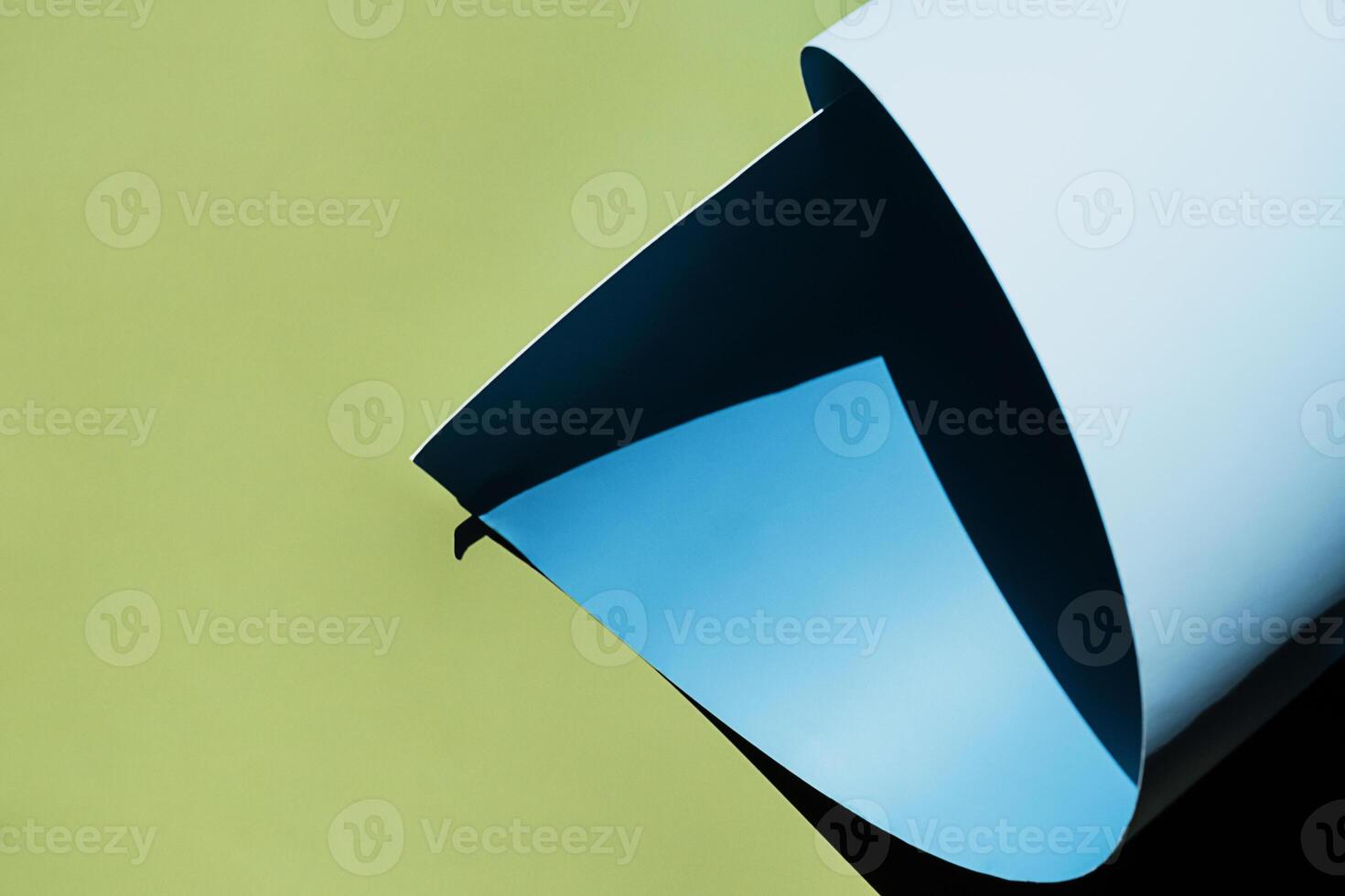Curled blue paper creating shadows on green background. photo