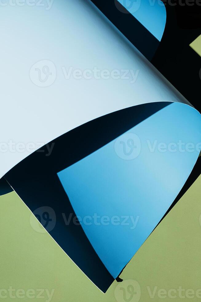 Curled blue paper creating shadows on green background. photo