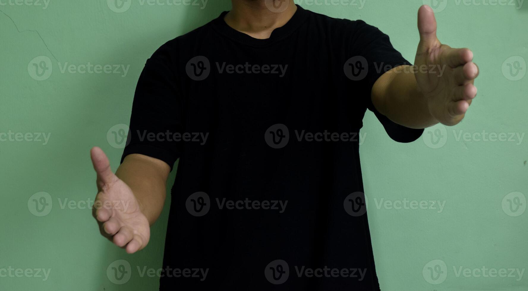 Young man greeting and hugging over on green background. Showing welcome gesture and holding empty raise hands photo