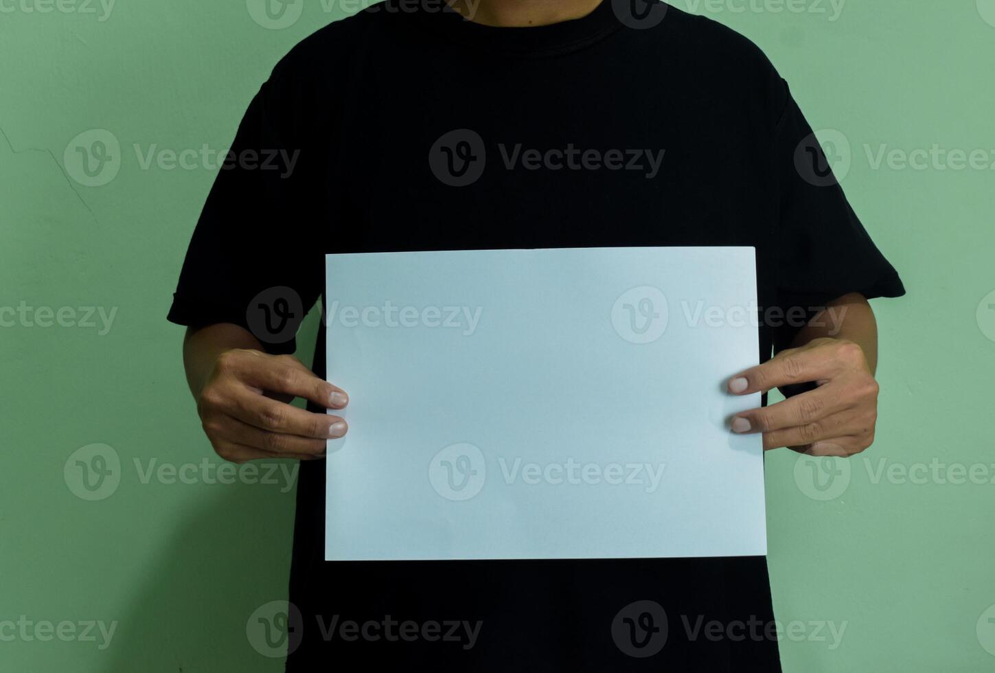 A man holding a blank piece of paper in horizontal orintaion. Mockup of person with statement or message photo