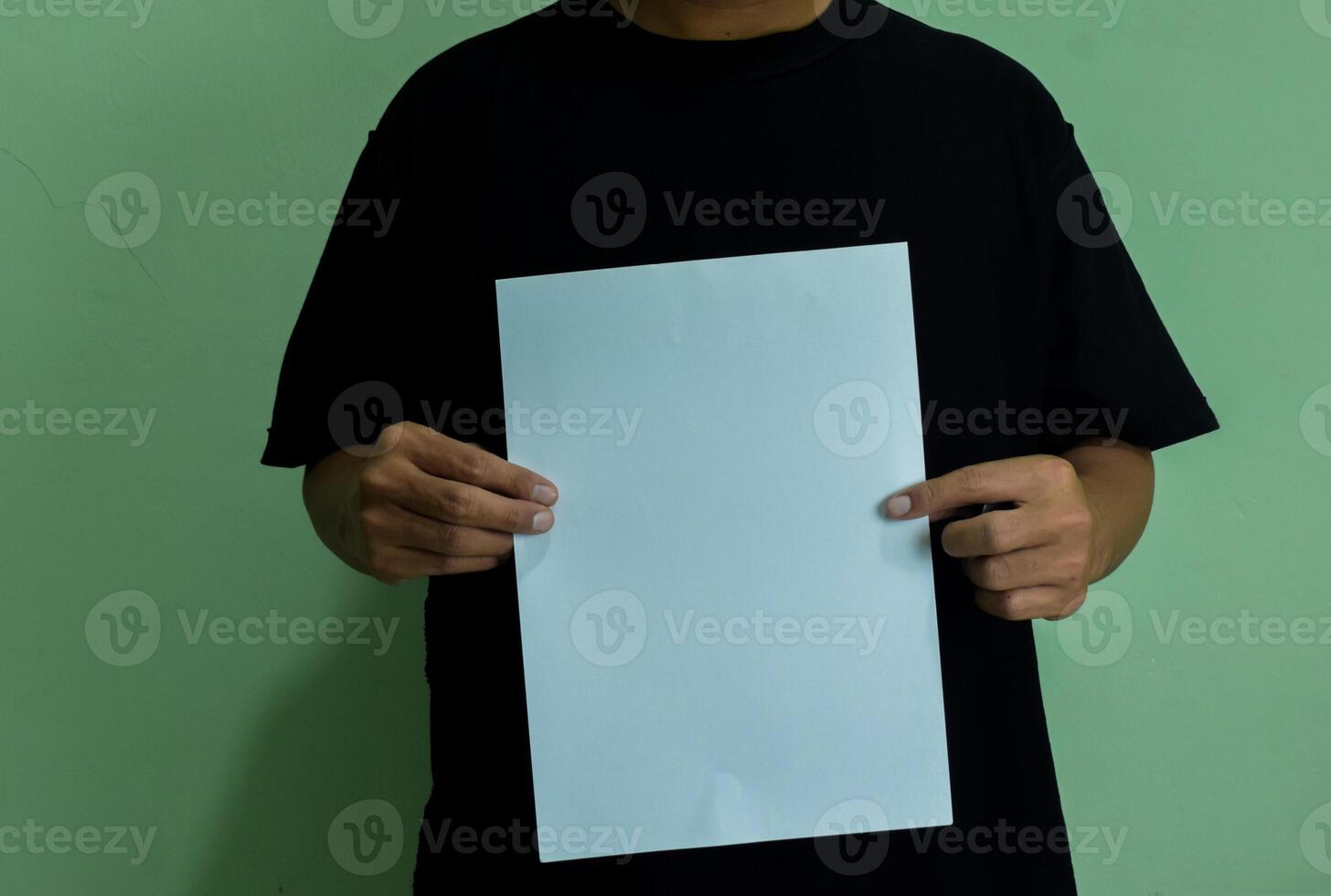 A man holding a blank piece of paper in vertical orintation. Mockup of person with statement or message photo